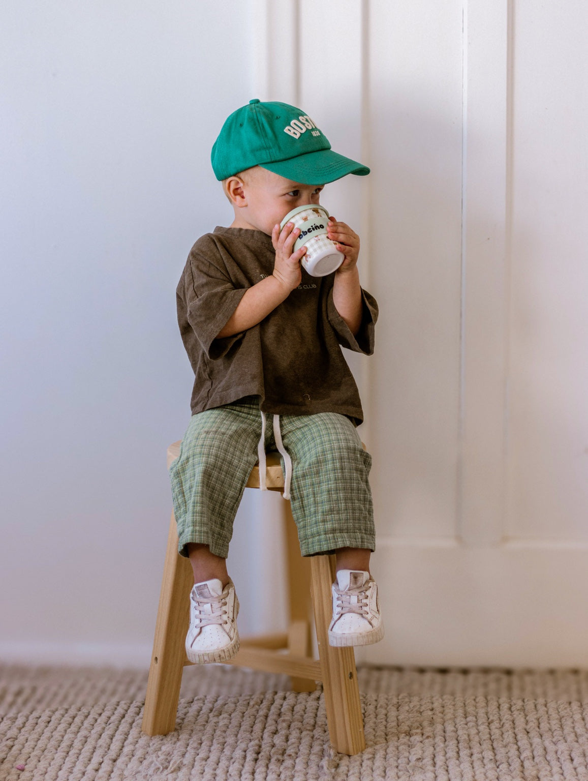 Boy sitting on a wooden chair drinking from a BBcino cup