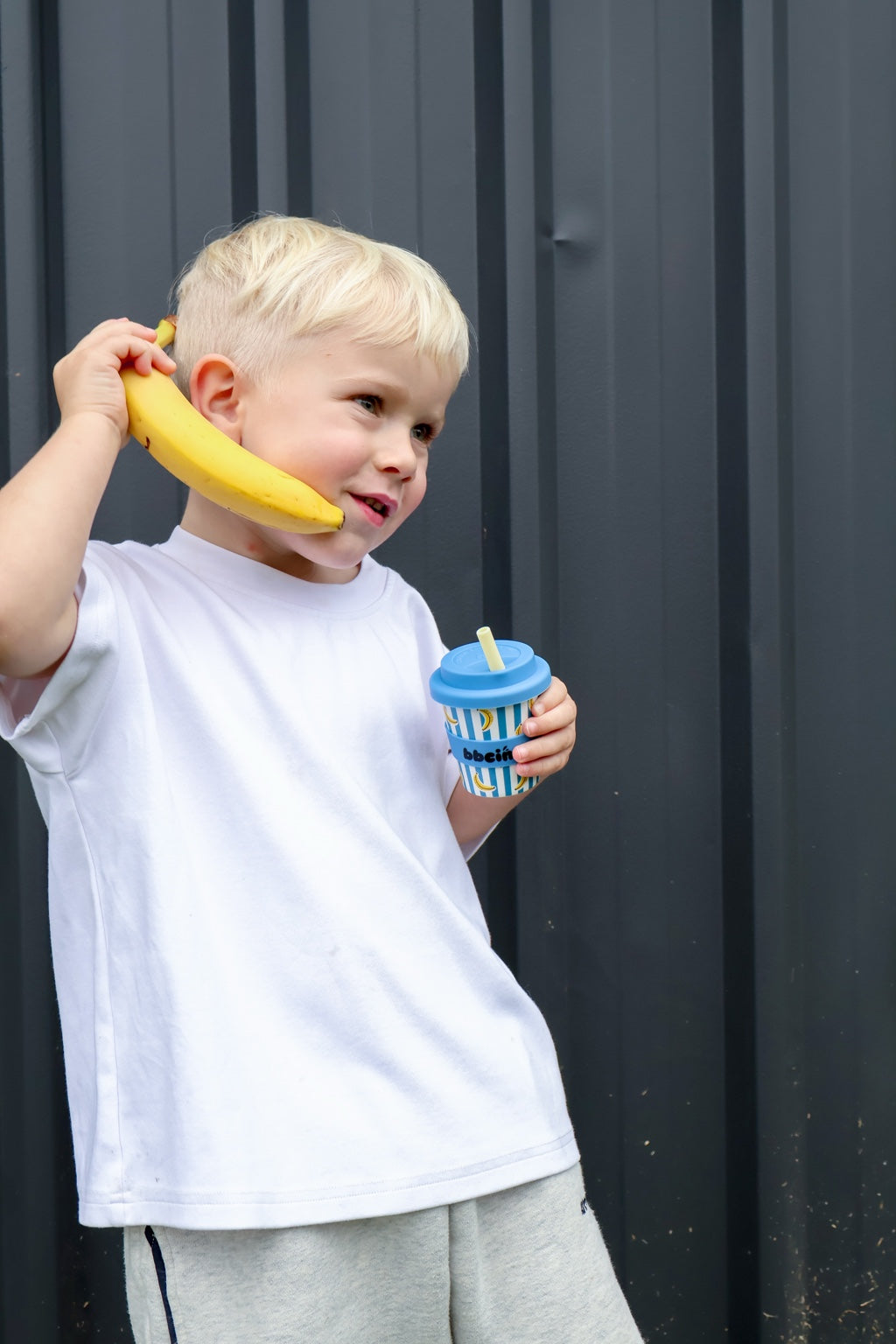 Child playing banana phone while holding a blue BBcino cup