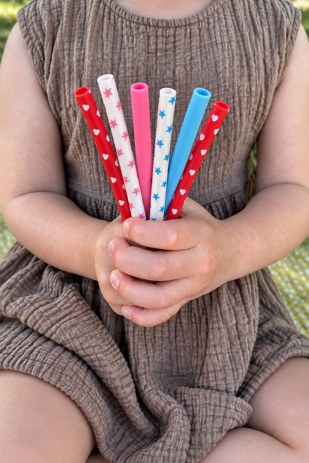 Six reusable patterned straws held in little hands