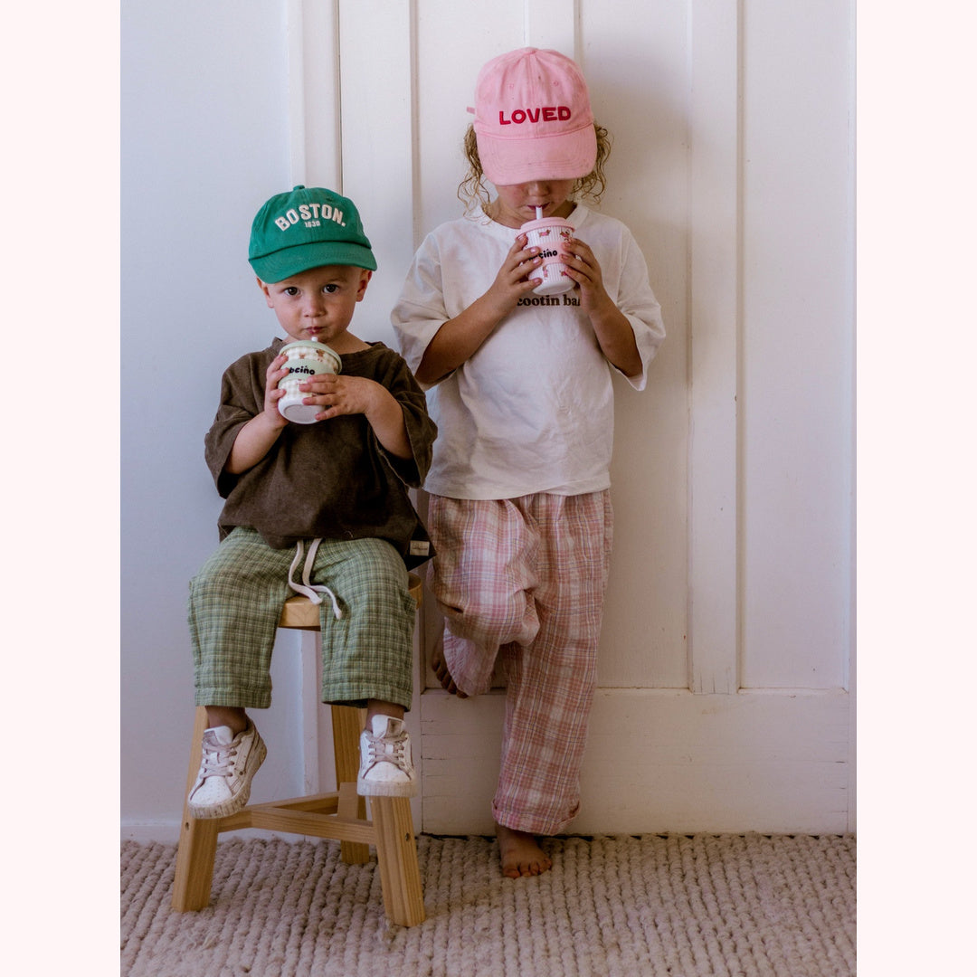 Two little sippers enjoying BBcino cups in green and pink caps