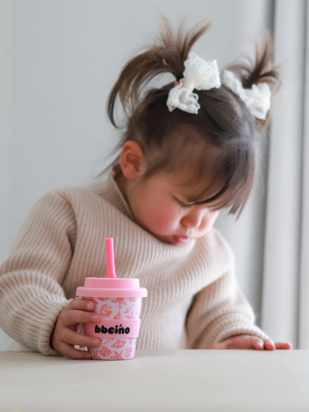 Girl with a bow holding her pink BBcino cup